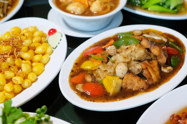 Several Chinese dishes arranged on white serving plates
