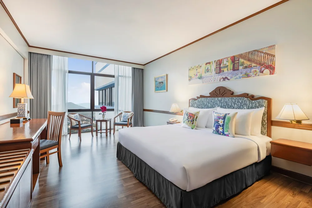 An Executive Suite bedroom with a large bed, desk and window-side chairs