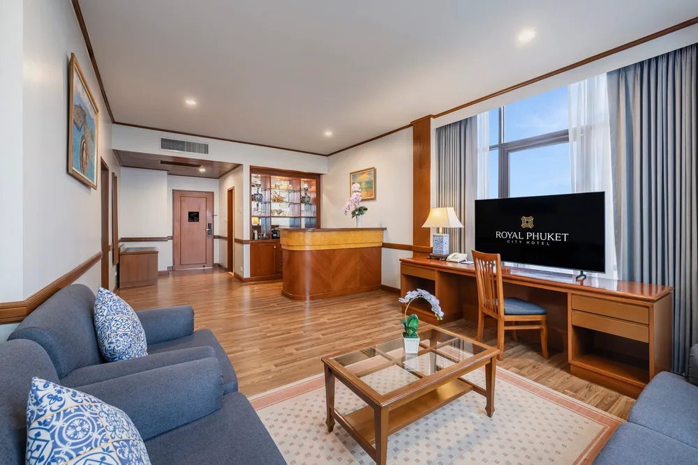 A hotel suite living area with sofas, a television and a dining counter