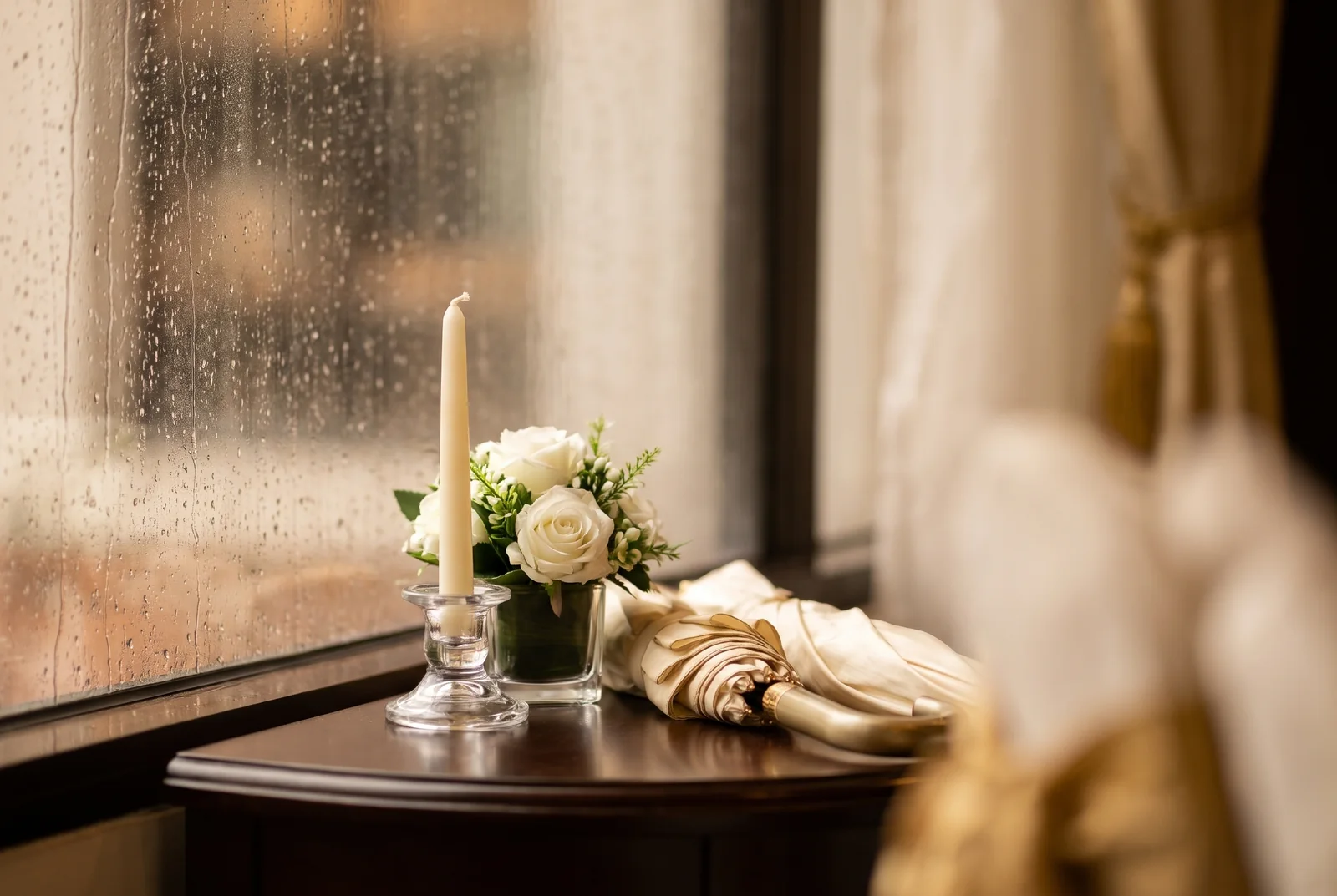 White flowers and candle beside a rain-speckled window — AI-generated editorial illustration