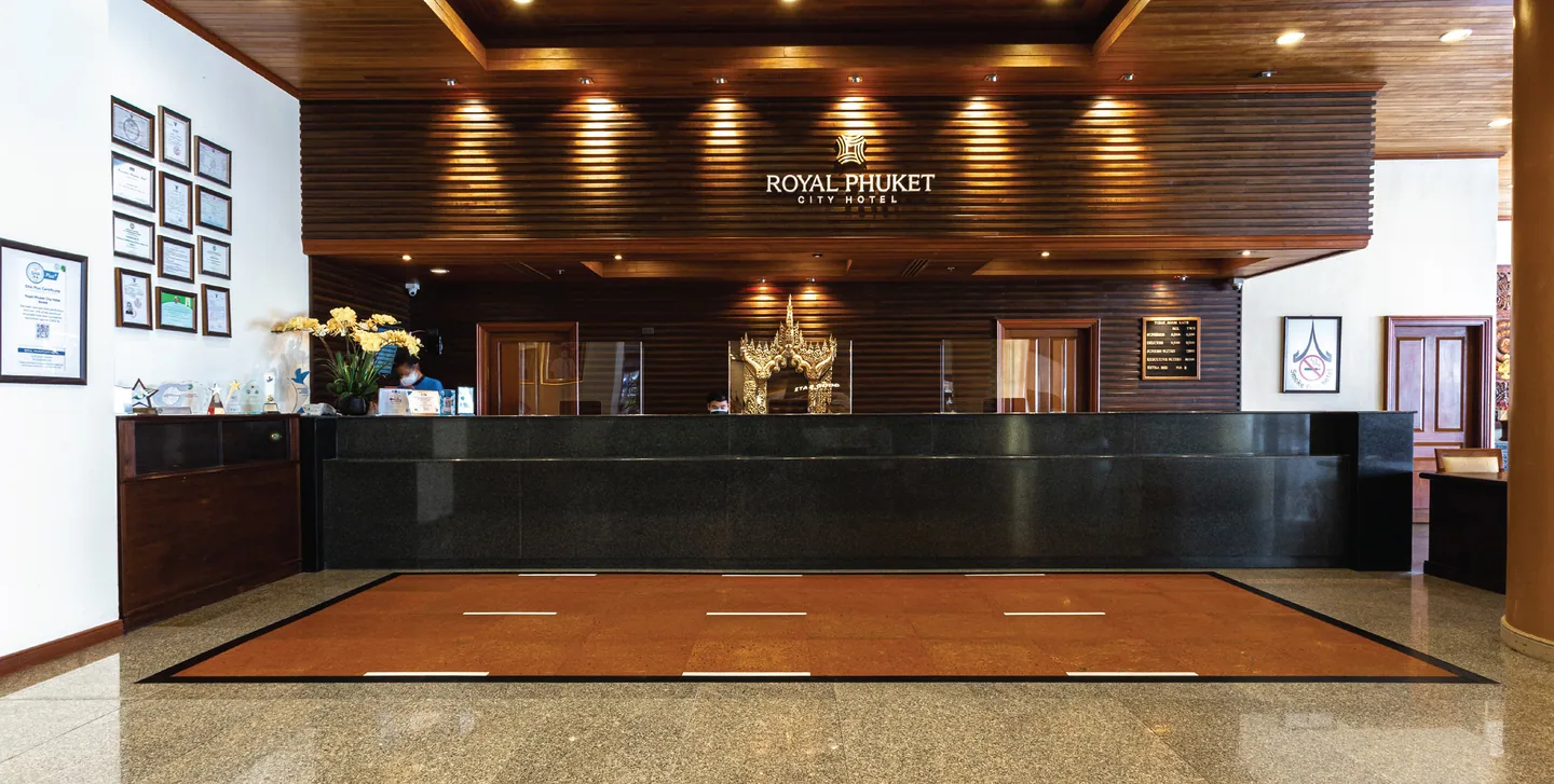 Royal Phuket City Hotel reception desk with the hotel's wooden feature wall