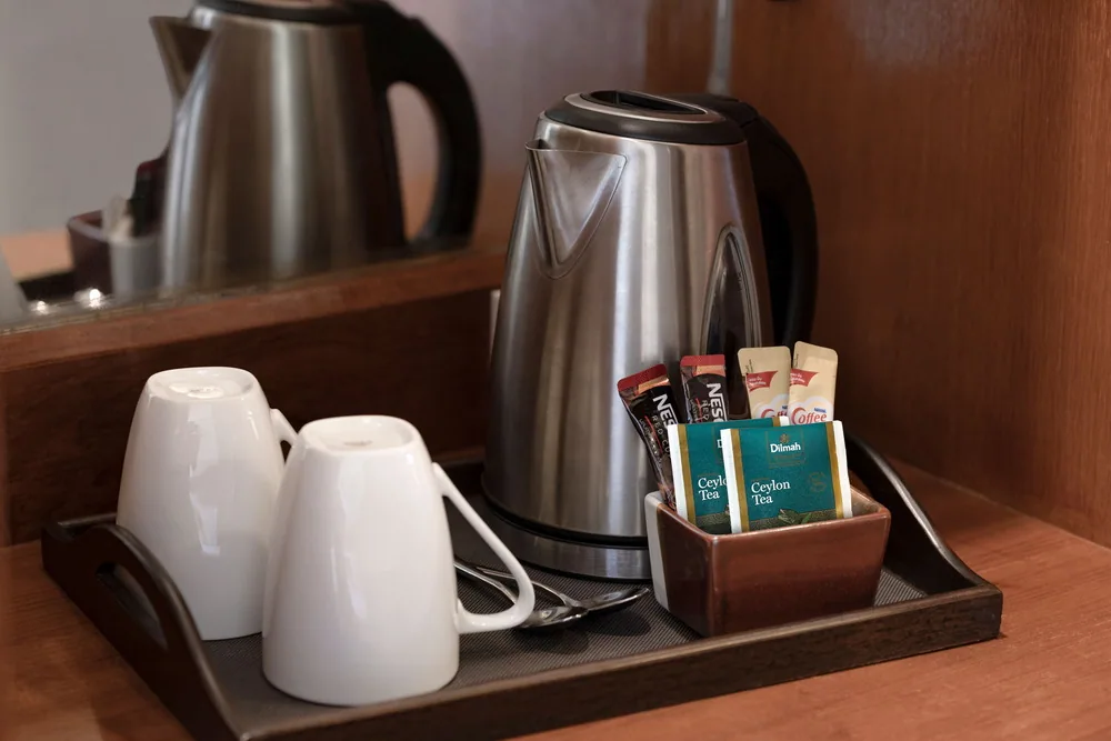 A kettle, cups and tea and coffee sachets photographed in a Royal Phuket City room