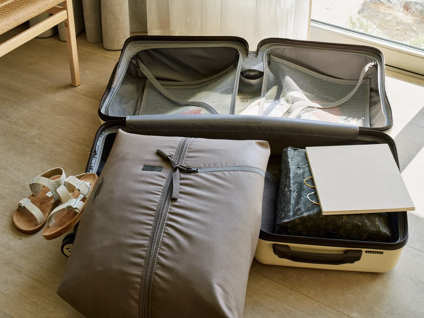 An open carry-on suitcase with packing cubes, sandals and a beach towel
