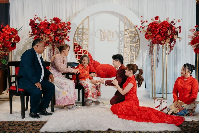 Relatives gathered around a couple in a decorated ceremony room