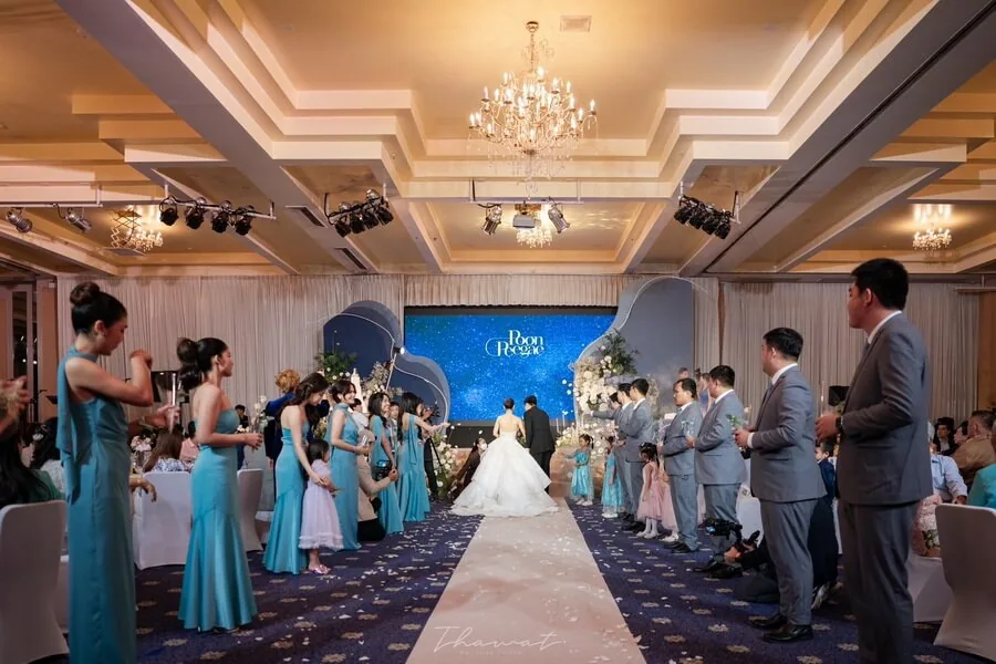 Guests standing beside an aisle as a wedding couple enters a ballroom