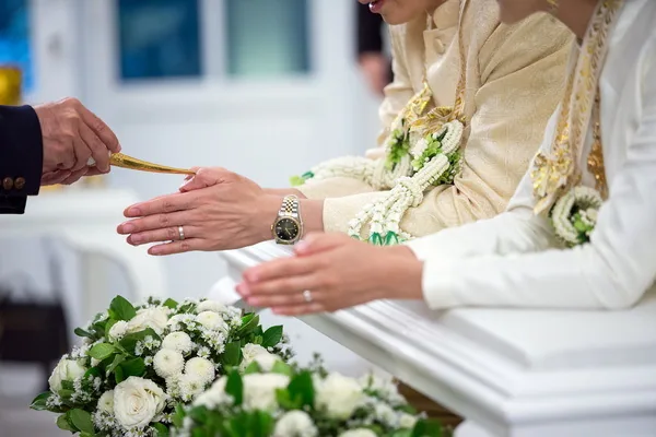 A close view of hands and white flowers during a wedding ceremony