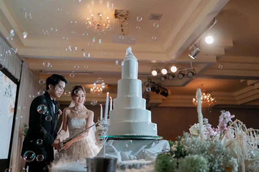 A couple standing beside a tiered wedding cake with bubbles around them