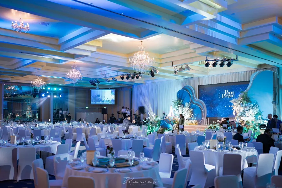 Round reception tables arranged in a ballroom with blue lighting
