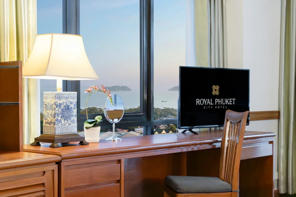 A desk, chair and lamp beside the window in a hotel room