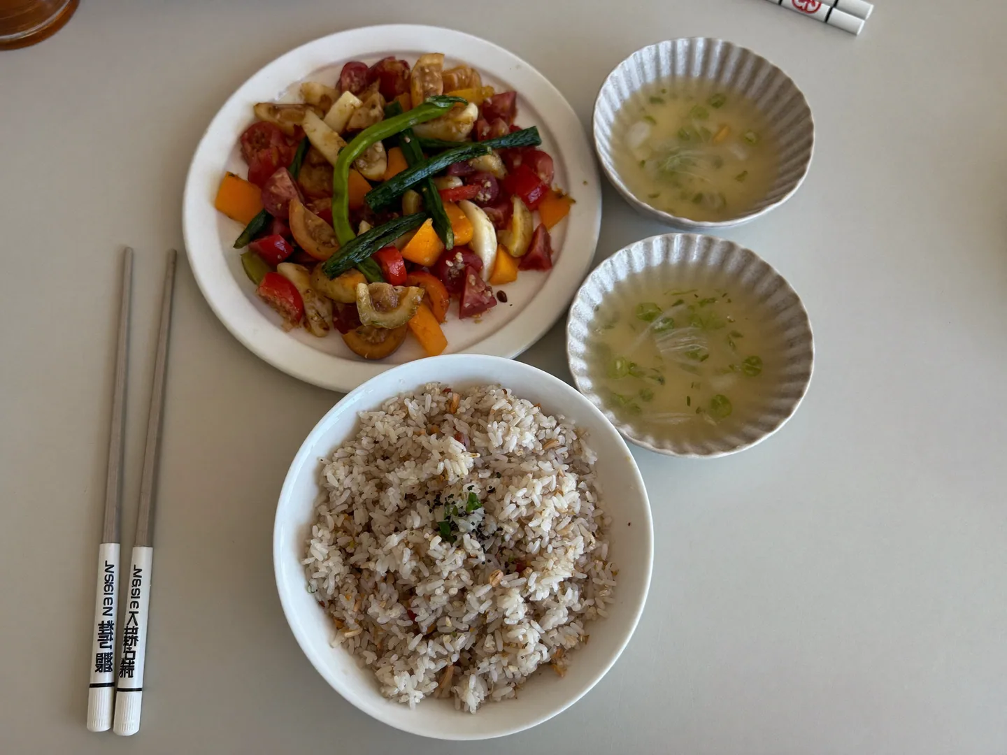 An illustrative shared-meal still life with rice, vegetables and ceramic serving bowls