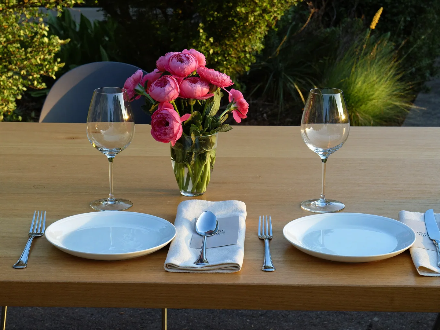 A dinner-planning table-setting concept with plain plates, glasses, linen and flowers