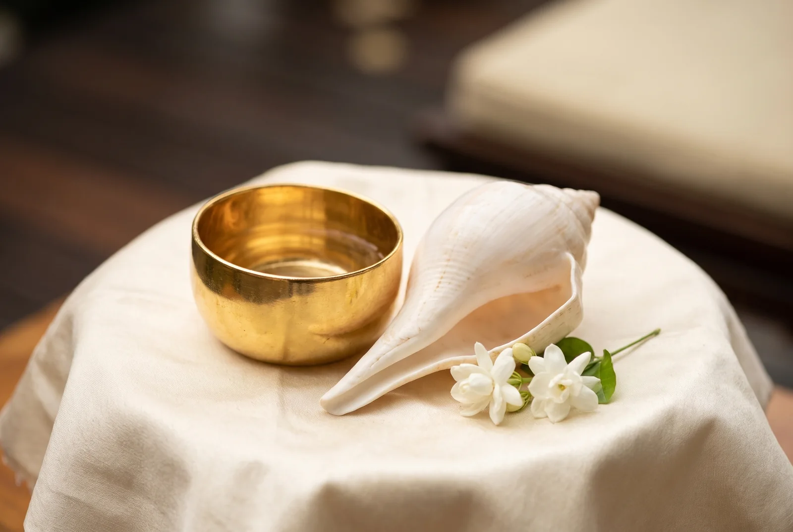 Conch shell, gold-tone water bowl and jasmine flowers — AI-generated editorial illustration