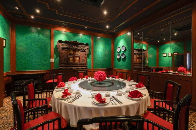 A round restaurant table set with plates and glassware in a room with green walls